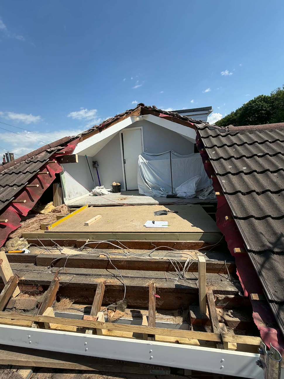 Bungalow roof opened up with tiles stripped back, exposing the roof timbers and loft space